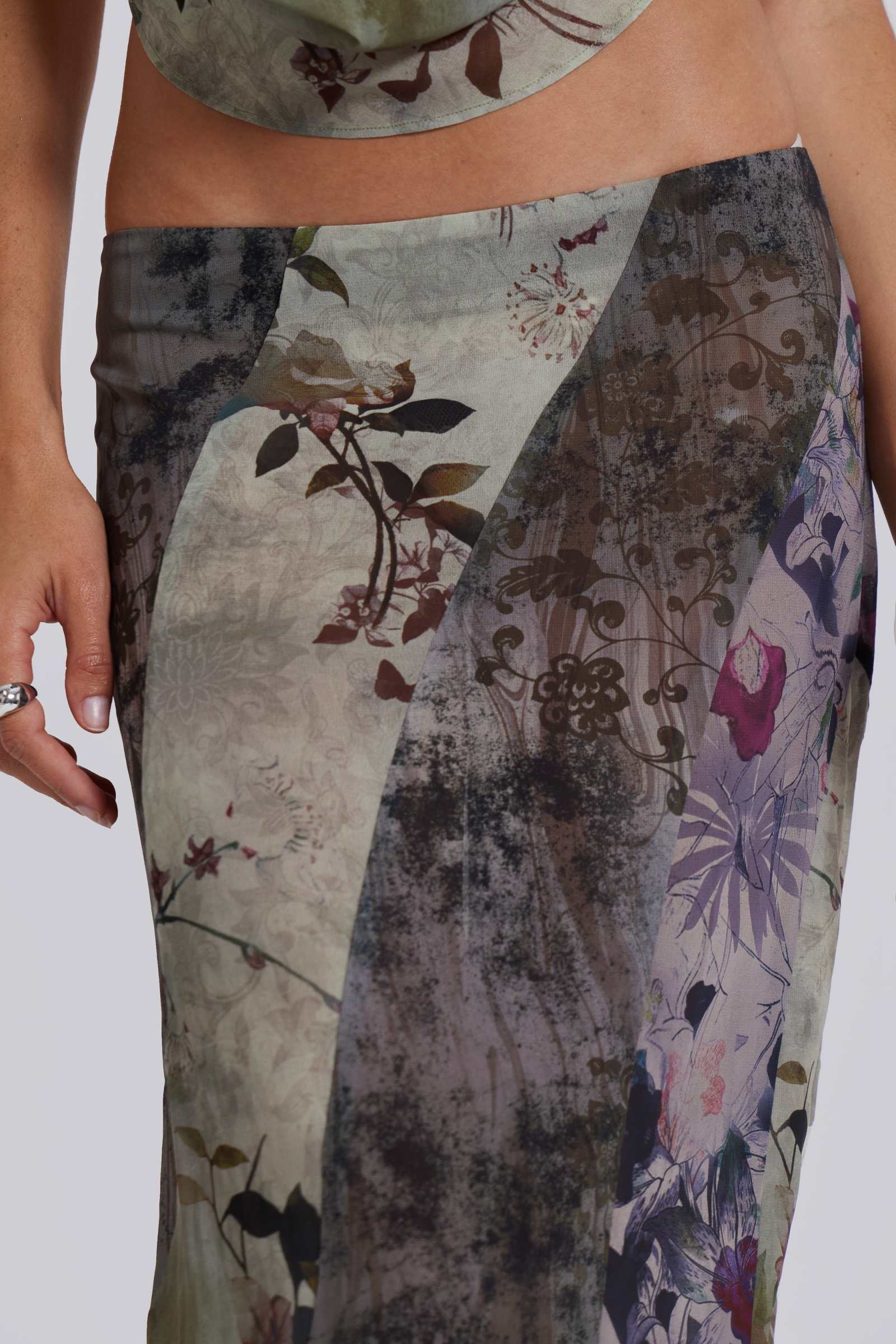 Female model wearing a floral maxi length skirt with panelled patchwork detail. Styled with the matching cowl neck top. 