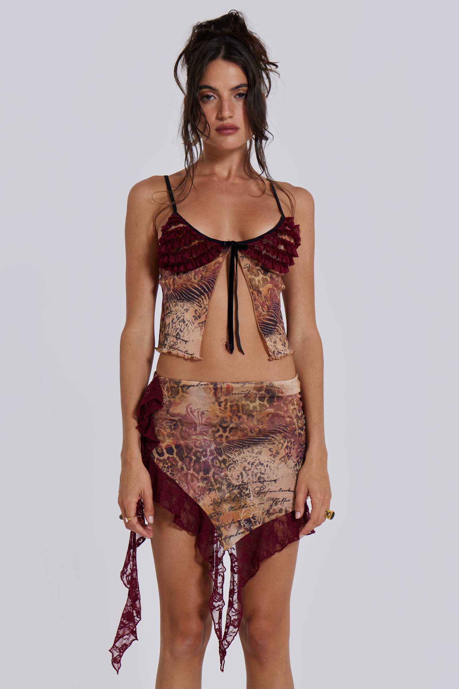 Female model wearing a leopard script print mesh mini length skirt with asymmetric hemline. Styled with the matching baby doll style top. 