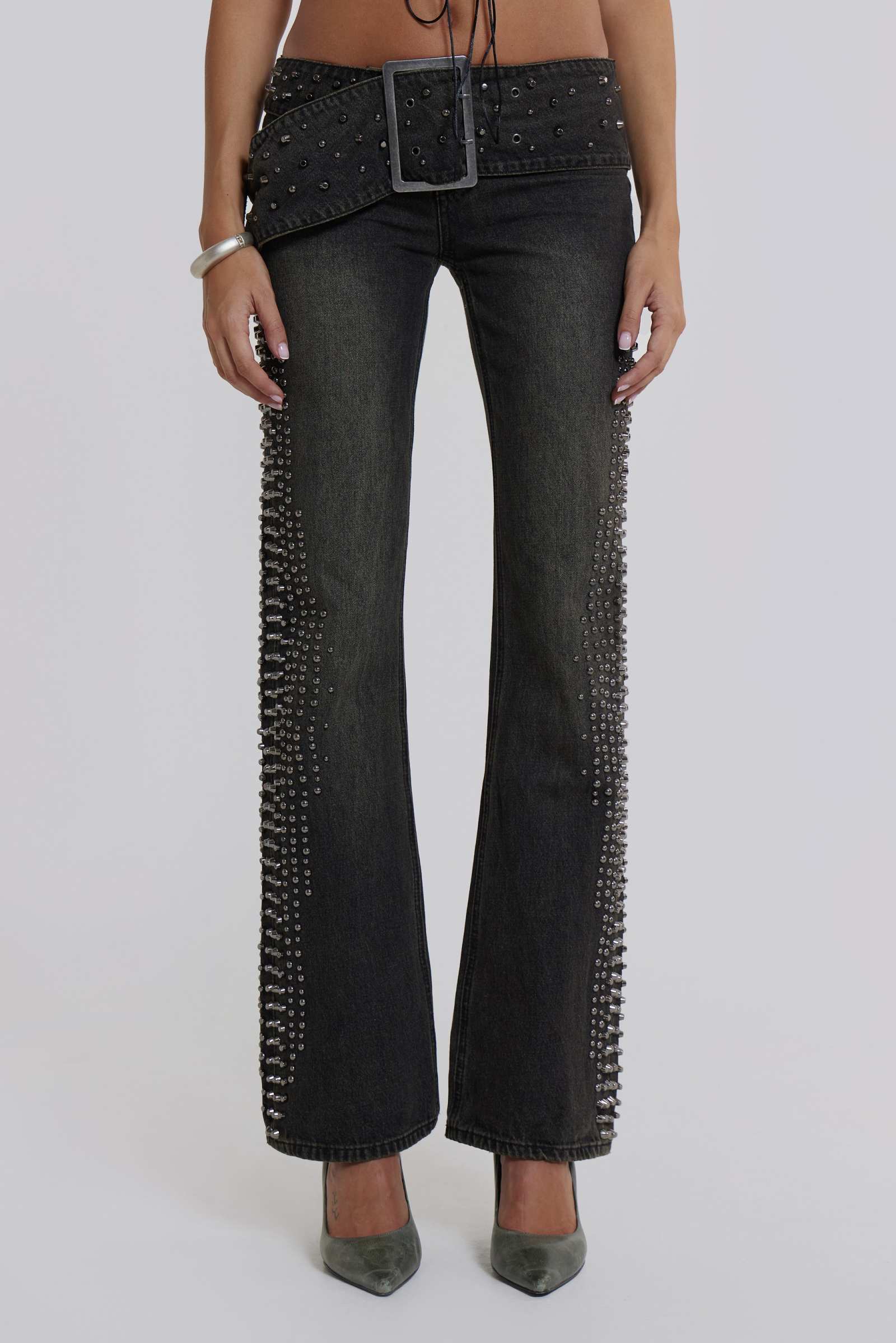 Female model wearing studded denim jeans with large buckle belt.