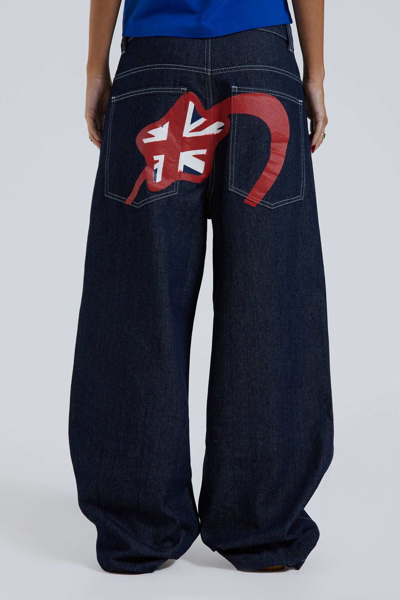 Female wearing sandblast washed denim jeans in an oversized skate fit with embroidered coin pocket and Union Jack artwork across back body and pockets. 