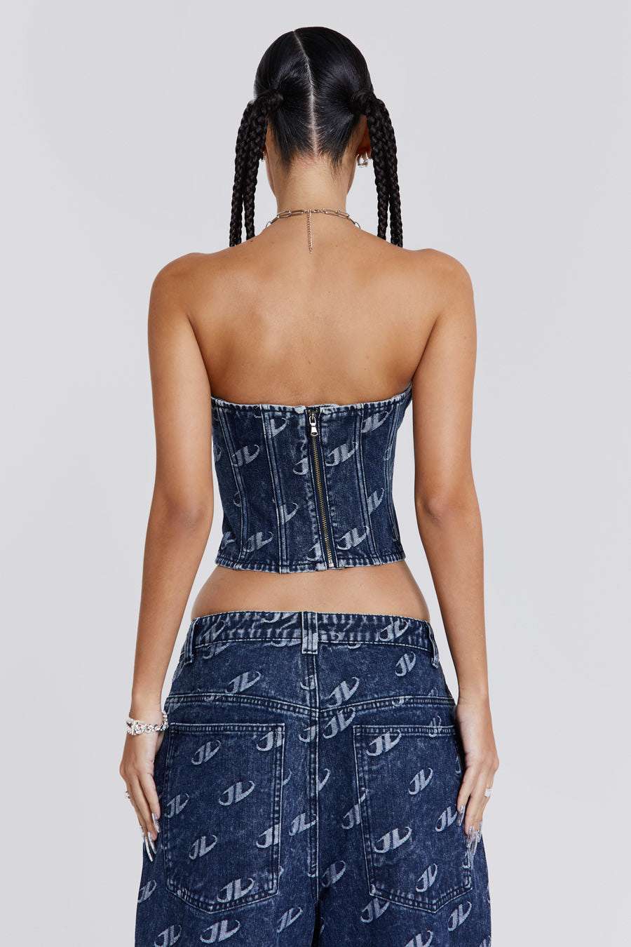 Female wearing a blue monogram embossed JL logo strapless corset top with a silver JL logo belt buckle detail. Styled with the matching baggy jeans. 