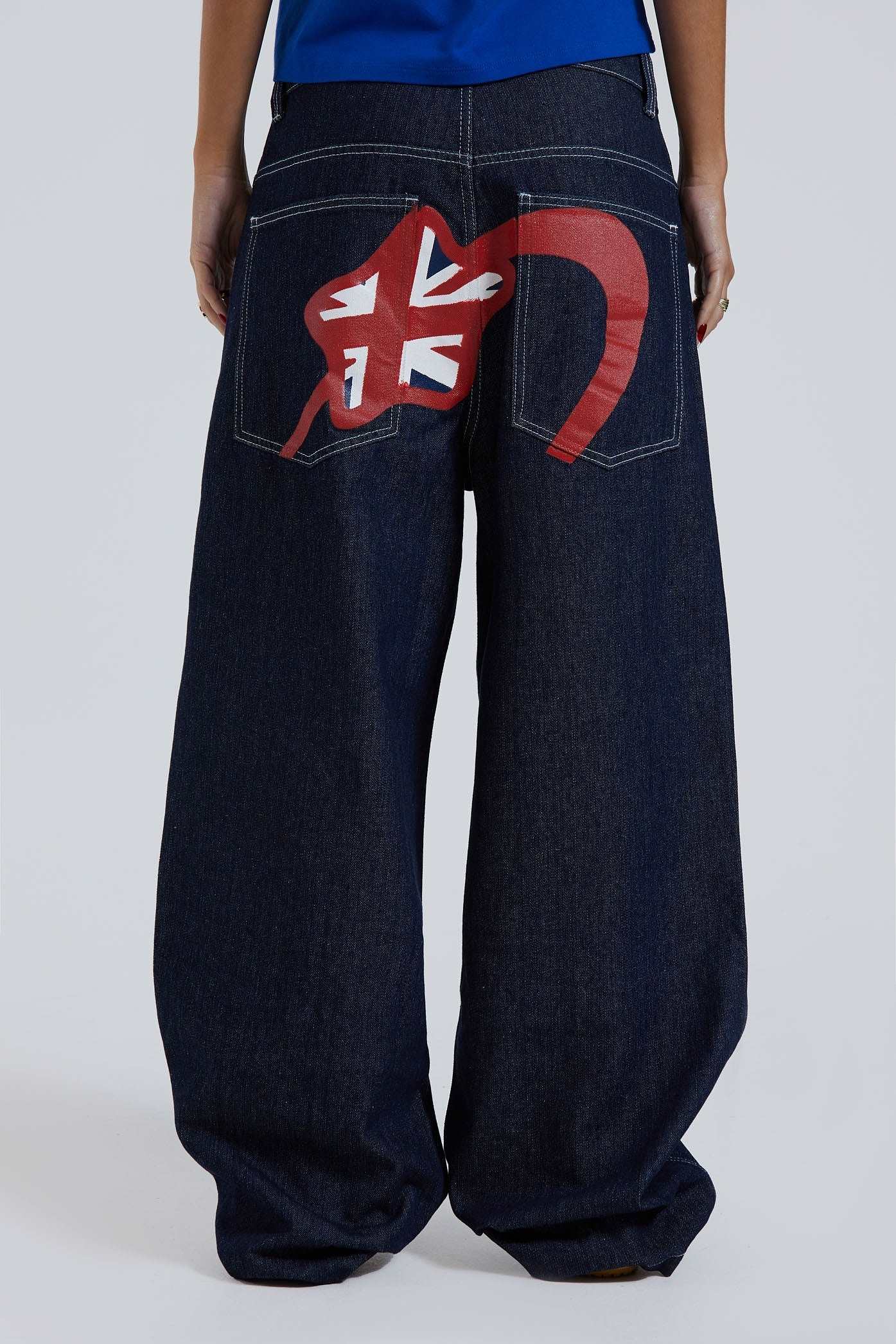 Female wearing sandblast washed denim jeans in an oversized skate fit with embroidered coin pocket and Union Jack artwork across back body and pockets. 